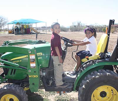 Two happy elementary students sitting on a tractor