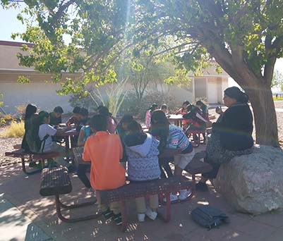 Group of students eating lunch outside with a staff member