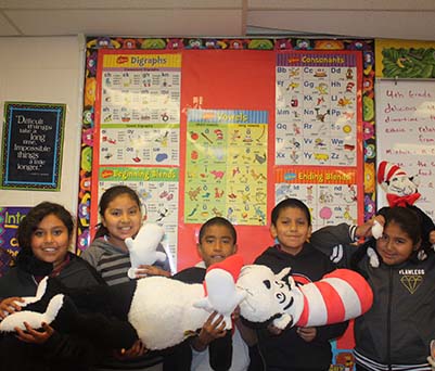 Happy students holding up a Dr. Seuss character
